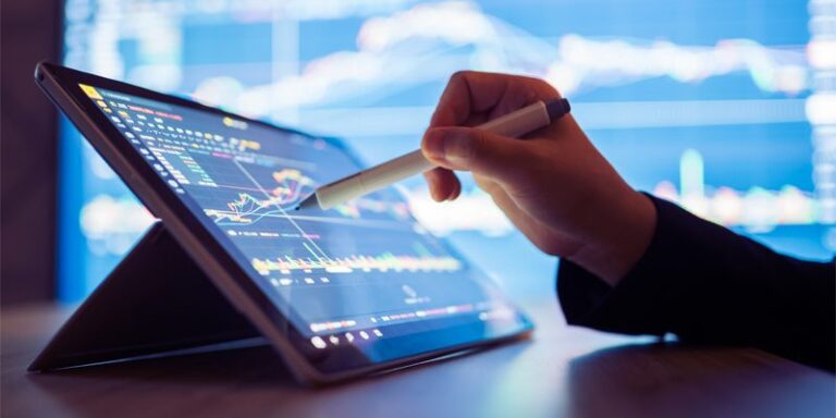 Hand using a tablet and stylus to track stocks.