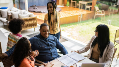 A family smiling while speaking with a business person.