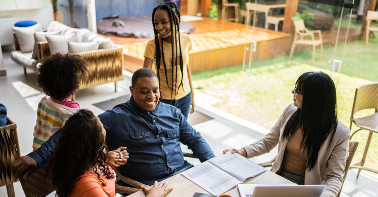 A family smiling while speaking with a business person.