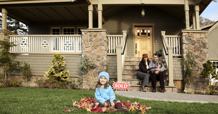 A family in front of their newly purchased home.