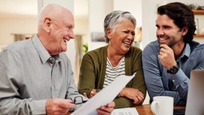 Parents and adult son laughing over documents.