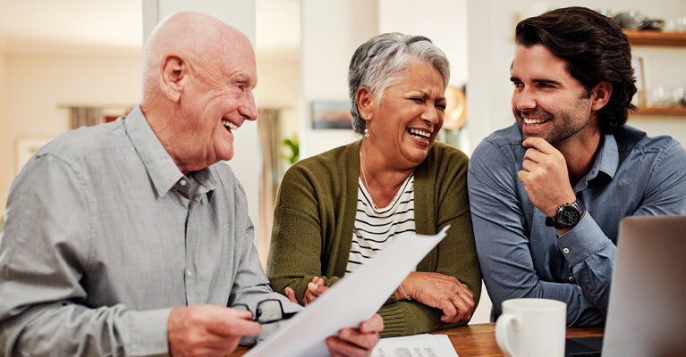 Parents and adult son laughing over documents.