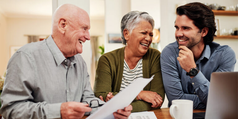 Parents and adult son laughing over documents.
