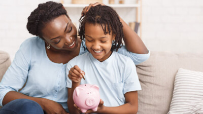 Woman and child putting coins into piggy bank.
