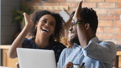 Woman and man high-fiving in front of laptop.