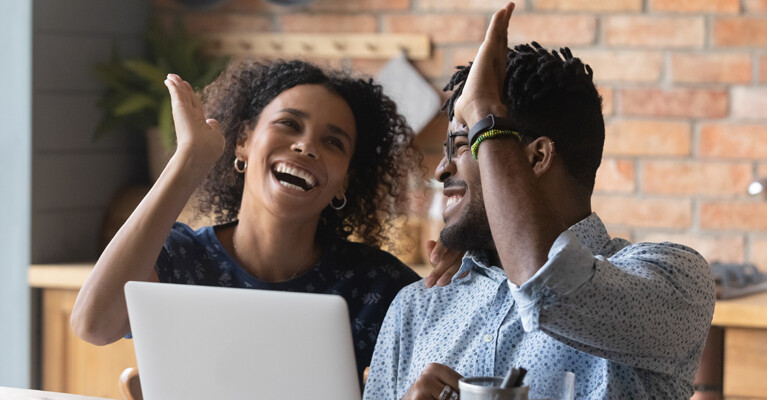 Woman and man high-fiving in front of laptop.