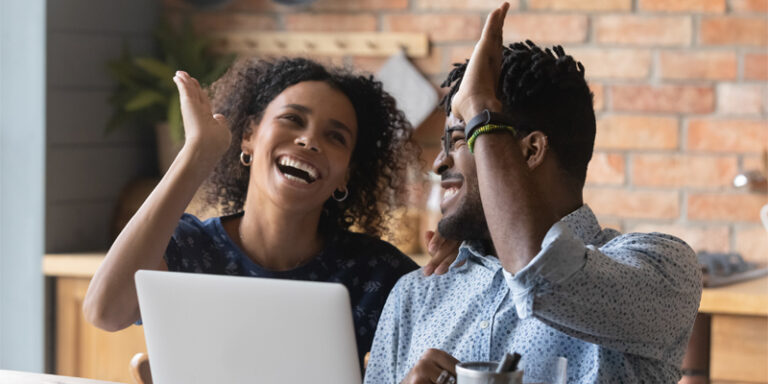 Woman and man high-fiving in front of laptop.
