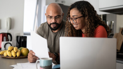 A couple using a laptop and reviewing documents.