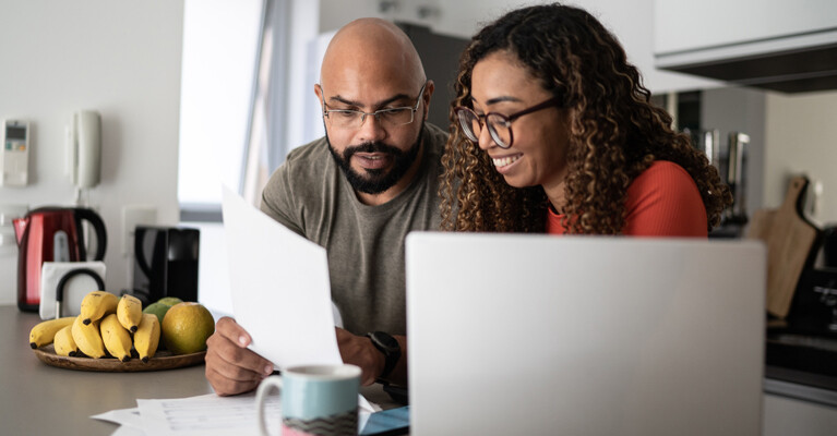 A couple using a laptop and reviewing documents.