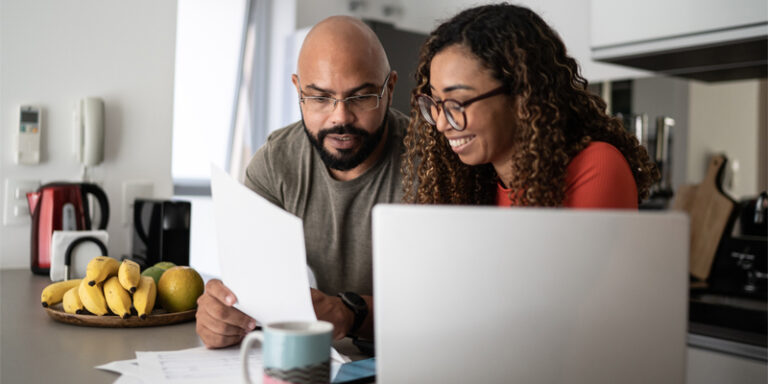 A couple using a laptop and reviewing documents.