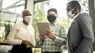 Woman and two men looking at a tablet.