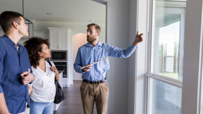A real estate agent walking a man and a woman through a house.