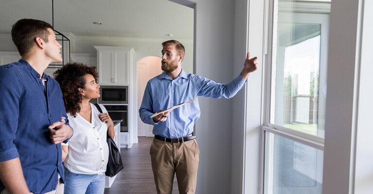 A real estate agent walking a man and a woman through a house.