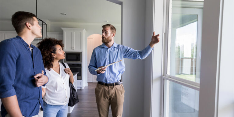 A real estate agent walking a man and a woman through a house.