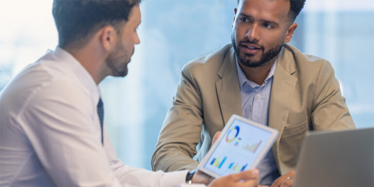 A businessman and a customer reviewing charts on a tablet screen.