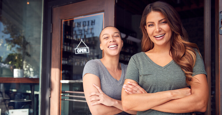 Two women standing in front of an open business.