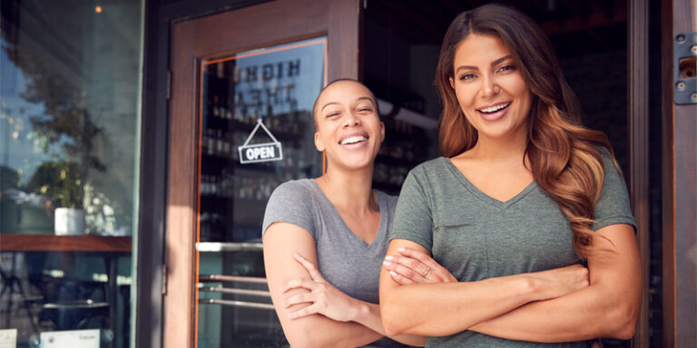 Two women standing in front of an open business.