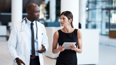 Doctor speaking to colleague with tablet computer.