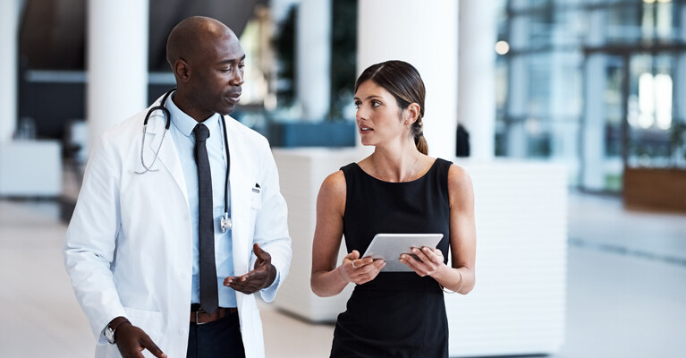 Doctor speaking to colleague with tablet computer.