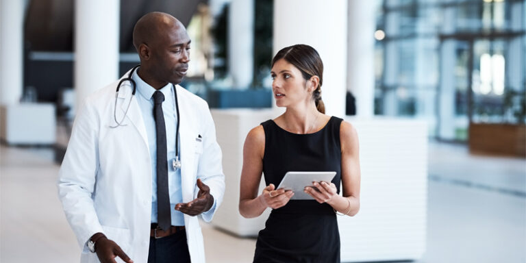 Doctor speaking to colleague with tablet computer.