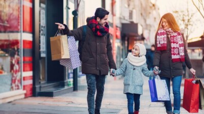 Man, woman, and child carrying shopping bags.