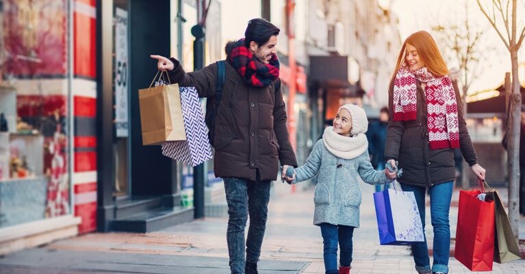 Man, woman, and child carrying shopping bags.