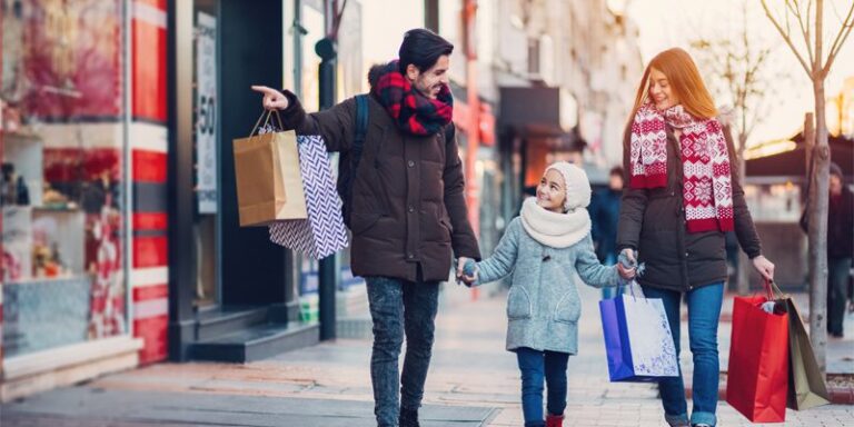 Man, woman, and child carrying shopping bags.