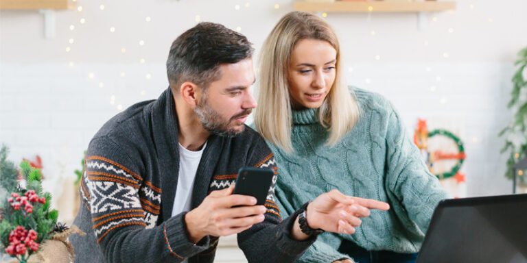 A couple budgeting and shopping for the holidays online.