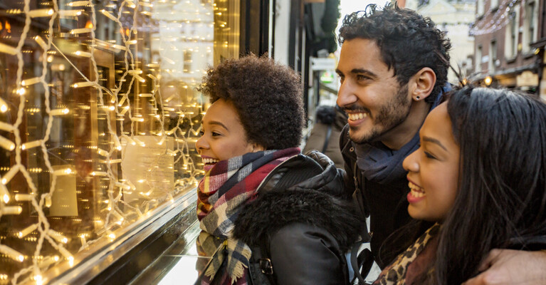 A family happily looks at a holiday window display.