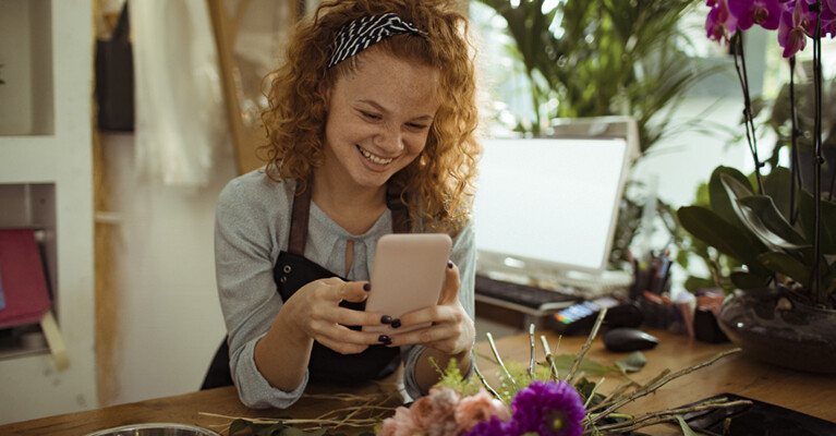 A florist smiling at her phone.