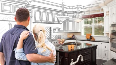 A couple embracing in front of an image of their kitchen, half of which is planned illustration and half of which is a photograph.