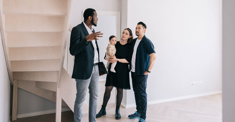 A real estate agent showing a property to a mother, father, and their baby.