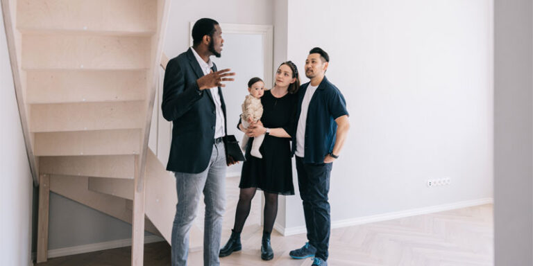 A real estate agent showing a property to a mother, father, and their baby.