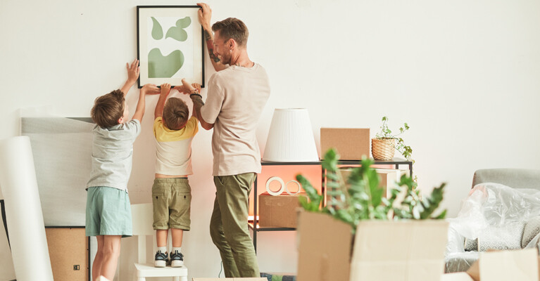 A family hanging a painting.