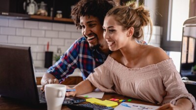 Man and woman excitedly using laptop computer.