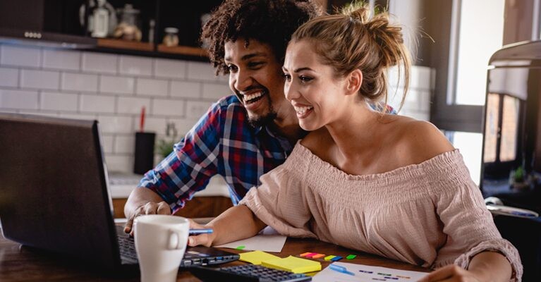 Man and woman excitedly using laptop computer.