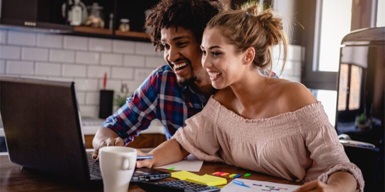 Man and woman excitedly using laptop computer.