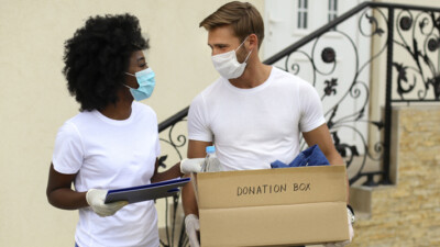 A man and a woman carrying a box of supplies to be donated to charity.