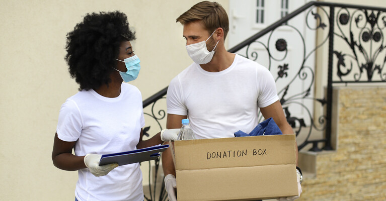 A man and a woman carrying a box of supplies to be donated to charity.