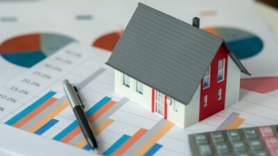 Model home on top of papers showing charts.