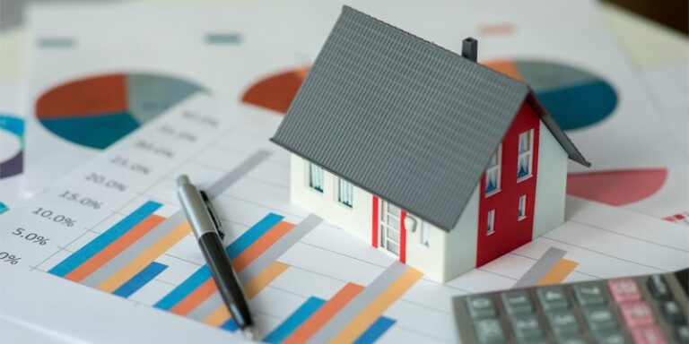 Model home on top of papers showing charts.