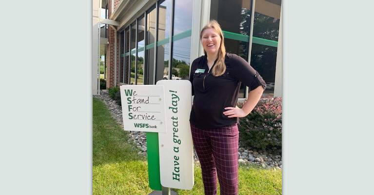 A WSFS Intern in front of a WSFS Bank sign.
