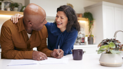 Man and woman laughing and smiling while filling out paperwork.