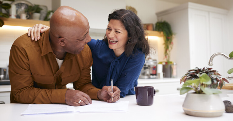 Man and woman laughing and smiling while filling out paperwork.