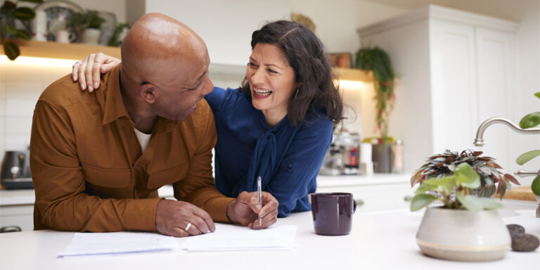 Man and woman laughing and smiling while filling out paperwork.