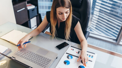 A businesswoman typing and reviewing charts.