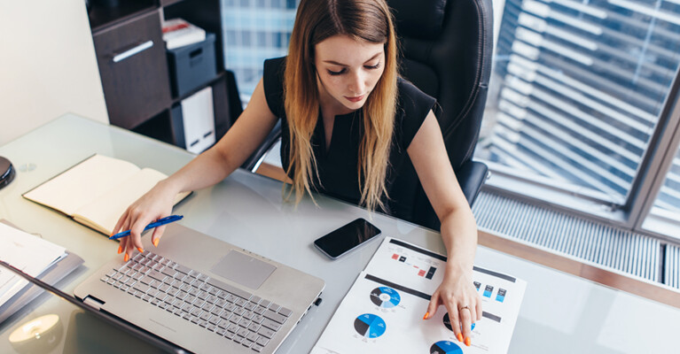 A businesswoman typing and reviewing charts.