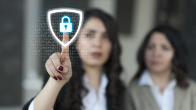 Two women touching a digital security icon.