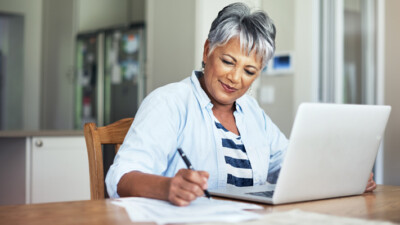 Woman using laptop and completing paperwork.