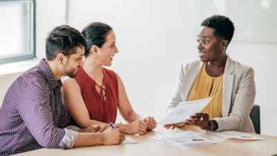 A real estate agent showing paperwork to a man and a woman.